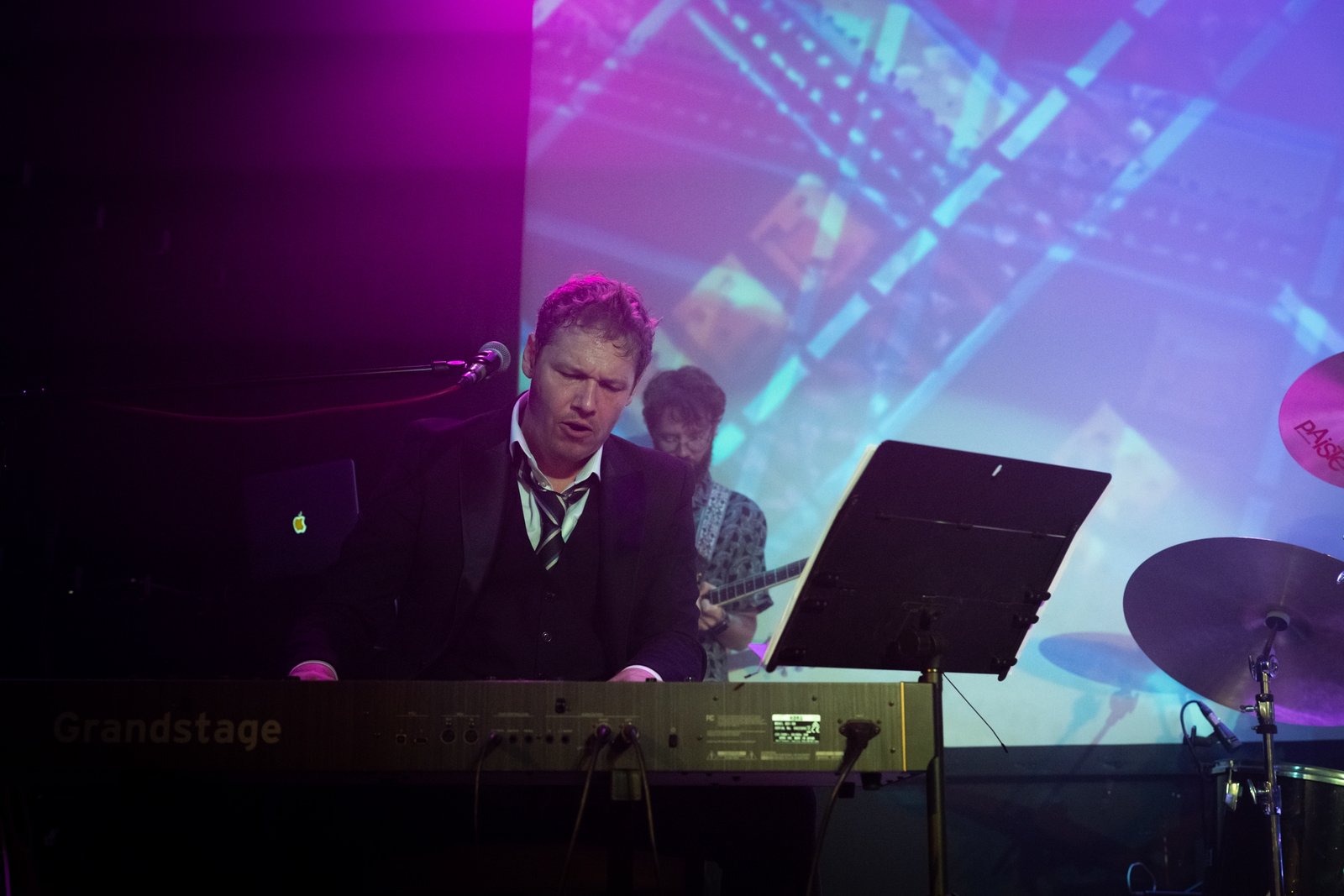 Rich Chance singing at a Korg Grandstage keyboard on stage, lit purple